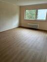 Wohnzimmer mit großem Fenster. Weißer Decke, tapezierfähigen Wänden und braunem Vinylboden..JPG - 