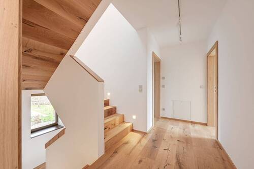 Das gemauerte Treppenhaus mit Stufenspots, Holzhandlauf und Deckenverkleidung sorgt für eine wohlige Atmosphäre - 