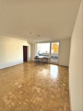 Wohnzimmer mit Parkettfußboden und Zugang zum großen Balkon - 3 Zimmer Etagenwohnung in Uelzen