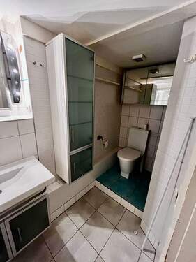 Badenzimmer mit Dusche, Waschbecken und WC - 
