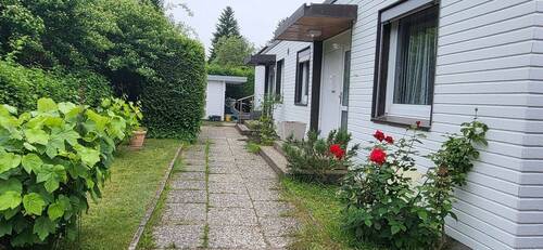Eingangsseite mit Vorgarten - Charmanter DHH-Bungalow in begehrter Wohnlage von Ahrensburg, 4 Zimmer, ca. 84 m² Wohnfläche, ca. 360 m² Grundstück, Vollkeller, Carport