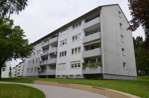 Akazienallee 12, Außenansicht vom Gehweg auf die helle Fassade eines mehrgeschossigen Wohngebäudes (Riegel) mit Satteldach - Ideal für Familien: 4-ZImmerwohnung mit Balkon in Baunatal-Baunsberg