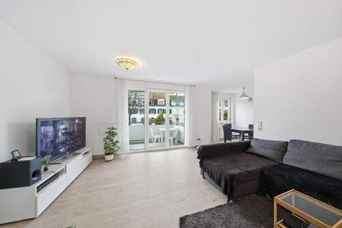 Wohnzimmer mit Zugang zum Balkon - Moderne 2-Zimmer-Eigentumswohnung im 1. Obergeschoss mit Balkon & Tiefgaragenstellplatz