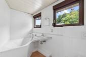Helles Badezimmer mit Badewanne und Tageslichtfenster - 