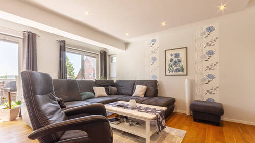 Das helle Wohnzimmer mit bodentiefen Fenster und Zugang zum Balkon - 