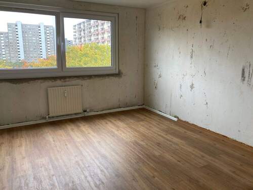 Schlafzimmer mit untapezierten Wänden und brauner Vinylboden in Holzoptik - 