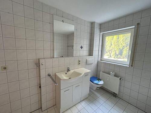 Badezimmer mit Waschmaschinenanschluss, Waschbecken, Badewanne, Dusche und WC - 