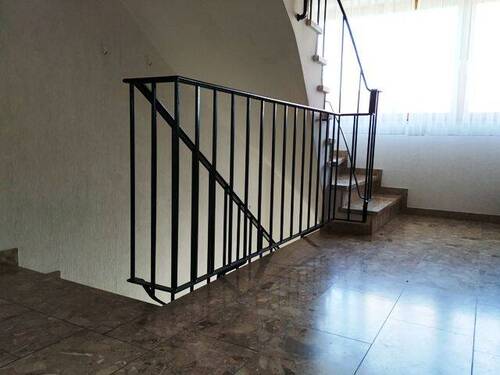 Treppenhaus mit Steinfußboden und Eisengeländer - 