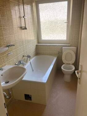 Tageslichtbad mit Badewanne, weißen Sanitärobjekten, gelben Wandfliesen und hellbraunem Linoleumboden - 