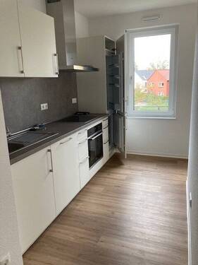 Küche mit Fenster, mit dunklen Boden gefliest und mit weißer Einbauküche ausgestattet- Beispielfoto - 