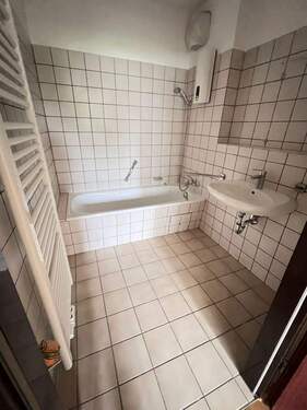 Bad mit Badewanne, weißem Waschbecken, weißem Fliesenspiegel und beigen Bodenfliesen - 2 Zimmer Etagenwohnung in Darmstadt