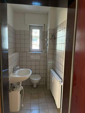 WC mit Fenster, wandhängendem WC, weißem Waschbecken und hellgrauen Wand- und Bodenfliesen - Etagenwohnung mit 58,60 m&sup2; in Darmstadt zur Miete