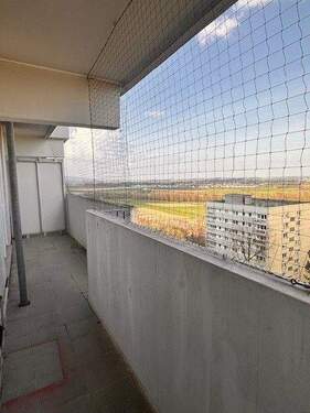 Balkon mit Taubennetz und Aussicht auf Wohnhäuser, Felder und Bäume.jpg - 