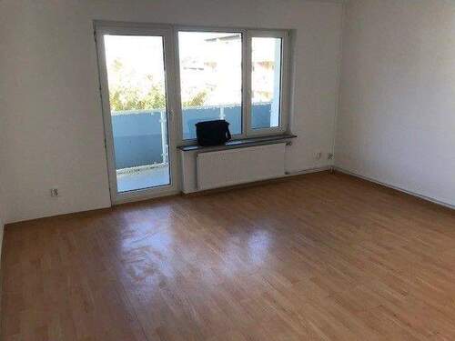 Wohnzimmer mit Zugang zum Balkon und PVC-Bodenlbelag in Holzoptik - 2 Zimmer Etagenwohnung zur Miete in Bad Vilbel