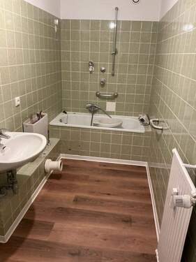 Bad mit grünen Wandfliesen, Bodenbelag in Holzoptik - 