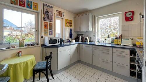 Die Einbauküche überzeugt mit funktionaler Aufteilung, ausreichend Stauraum und großen Fenstern - 