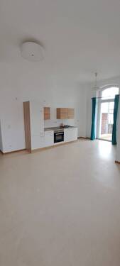 Wohnraum mit offener Küche u. Zugang Balkon - 