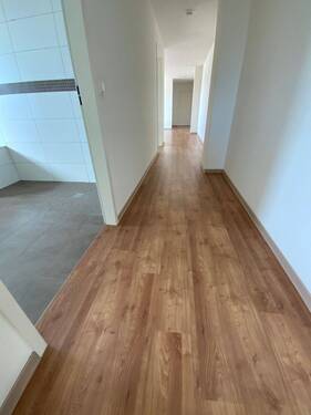  Blick Eingang in die Diele mit braunem PVC-Boden und weißen Wänden - 