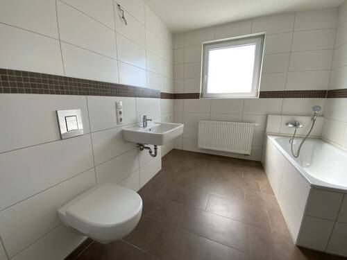 Blick von Diele in Schlafraum mit braunem PVC-Boden und weißen Wänden mit weißem Fenster - 