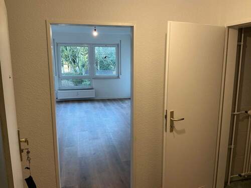 Flur mit neuem Fußbodenbelag in Holzoptik, Wände tapeziert und weiß angelegt - 