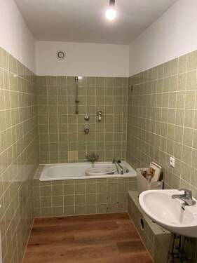 Badezimmer mit grünen Wandfliesen, Bodenbelag in Holzoptik - 1 Zimmer Etagenwohnung in Wiesbaden