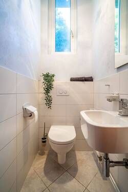 Das Gäste-WC ist in hellen Cremetönen gefliest. - 