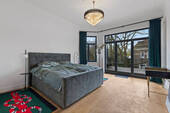Hauptschlafzimmer mit großer Fensterfront und Balkon - 