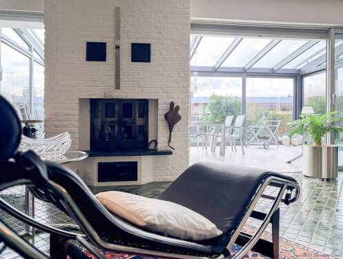 Wohnbereich mit Kamin und Blick in den großzügigen Wintergarten - 
