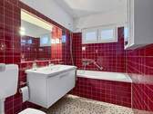 Gefliestes Badzimmer mit Badewanne und moderner Ausstattung - 