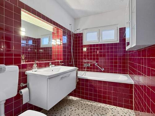 Gefliestes Badzimmer mit Badewanne und moderner Ausstattung - 