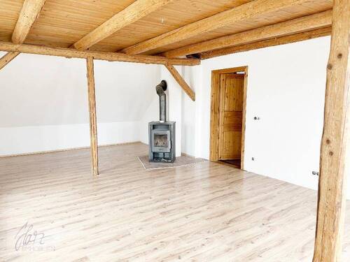 Wohnzimmer mit Kaminofen & Holzbalkendecke, Blick Richtung Flurbereich - untere Wohnebene - 6 Zimmer Etagenwohnung zur Miete in Riesa
