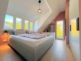 Schlafzimmer mit großer Fensterfront und Balkon - 