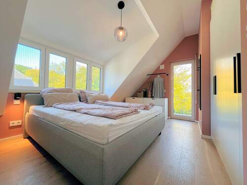 Schlafzimmer mit großer Fensterfront und Balkon - 