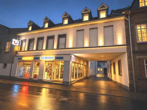 Abendliche Straßenszene mit Reisebüro.png - Frei ab sofort 2-Zimmer-Wohnung im 1. Obergeschoss Einbauküche Ohne Balkon Ohne PKW-Stellplatz