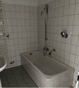 Innenliegendes Badezimmer mit Wanne und wandhängendem WC, helle Wand- und Bodenverfliesung.JPG - 