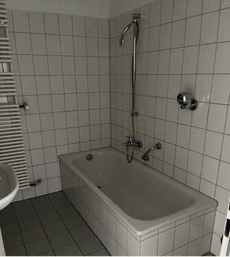 Innenliegendes Badezimmer mit Wanne und wandhängendem WC, helle Wand- und Bodenverfliesung.JPG - 
