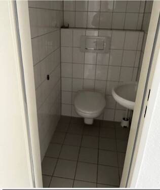 Gäste-WC mit wandhängendem Toilettenbecken, helle Boden- und Wandverfliesung.JPG - 