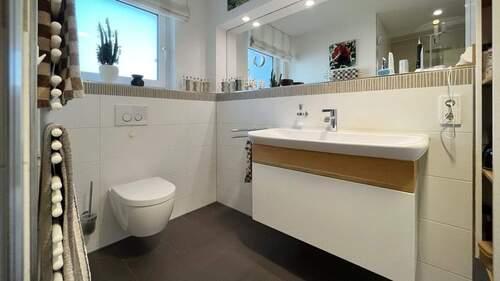 Tageslichtbad mit großformatigen Fliesen und modernen Armaturen - 