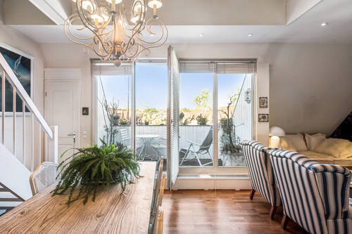 Blick aus der Küche in den offenen Ess- und Wohnbereich mit Zugang auf den Balkon - 