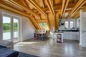 Dachgeschoss-Wohnzimmer mit offenem Dachstuhl und Balkonzugang - 