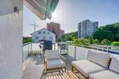 Großzügiger Balkon mit Glasgeländer und Holzdeck - 