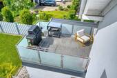 Balkon-Vogelperspektive: Holzdeck mit Glasgeländer über dem Garten - 