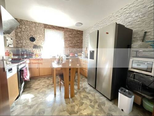 Küche mit Steinwänden und Essbereich - 