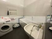 Modernes Badezimmer mit Badewanne und Waschmaschine - 