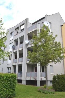Lindenallee 23, Außenansicht über die Grünanlage mit altem Baumbestand auf die südlich ausgerichteten Balkone eines Wohngebäudes mit heller Fassade. - 3 Zimmer Etagenwohnung in Baunatal