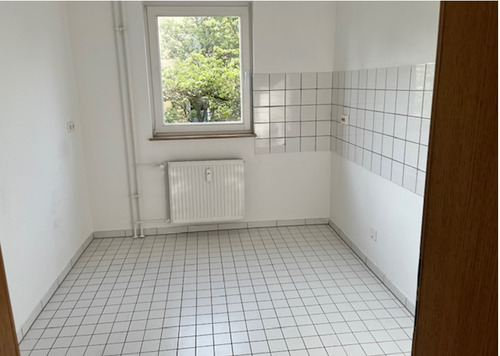 Küche mit Blick in Richtung Fenster, helle Wände, helle Bodenfliesenund heller Fliesenspiegel.PNG - 