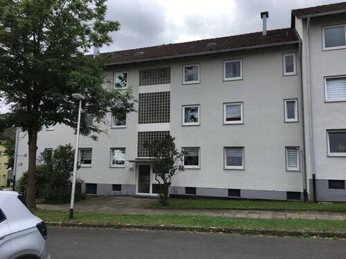 Akazienallee 20, Außenansicht auf den Eingangsbereich eines mehrgeschossigen Wohngebäudes mit heller Fassade und Satteldach - Großzügige 4-Zimmerwohnung mit Sonnenbalkon in Baunatal-Baunsberg