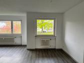 Großzügiger Wohn- und Essbereich mit Zugang zum Balkon, hellen Wänden und hellem PVC-Bodenbelag in Holzoptik.PNG - 3 Zimmer Etagenwohnung in Baunatal