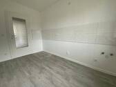 Blick von Diele in Küche mit weißen Fliesenspiegel und weißen Wänden, weißen Fenstern und grauem PVC-Boden.jpg - 