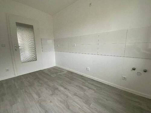 Blick von Diele in Küche mit weißen Fliesenspiegel und weißen Wänden, weißen Fenstern und grauem PVC-Boden.jpg - 
